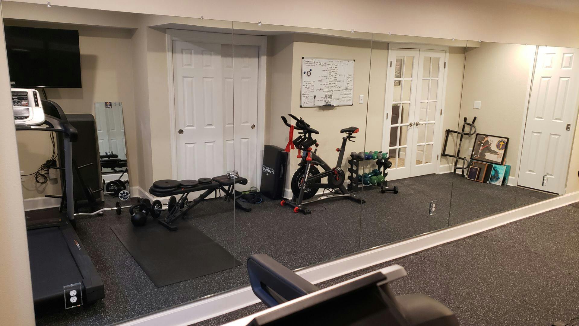 Large workout mirror reflecting gym equipment in a home fitness area