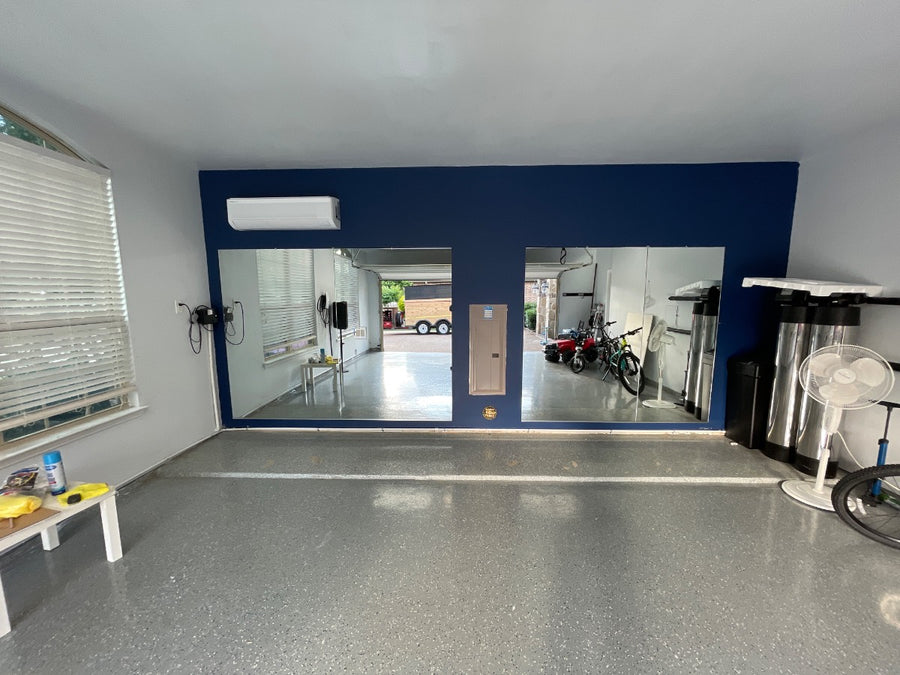 Four 48 by 72 inch mirrors across the back wall of a two-car garage gym near Dallas