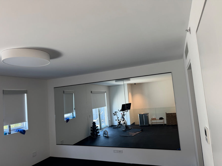 Three 48 by 72 inch safety-backed mirrors hung edge to edge in a Chicago home gym